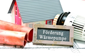Modellhaus mit Heizungsthermostat als Symbol für Förderung von Wärmepumpen